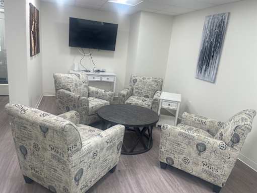 A living room with a TV and chairs.