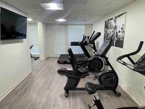 A gym room with treadmills, exercise bikes, and a television.