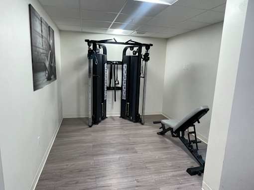 A gym room with a bench, weights and a picture on the wall.