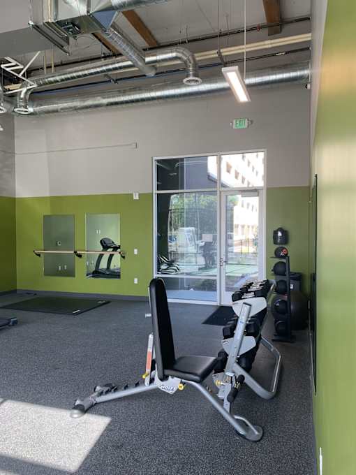 A gym with a green wall and gym equipment.