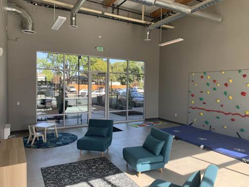 A room with a climbing wall and chairs.