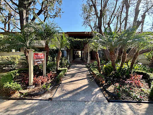 A pathway leads to a building with a sign that reads  at The Arbors Santa Ana, California, 92705