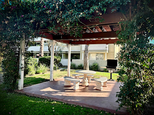 A patio with a table and chairs under a canopy. at The Arbors Santa Ana, California, 92705