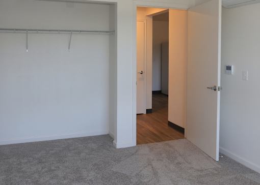 A room with a white wall and a grey carpet.