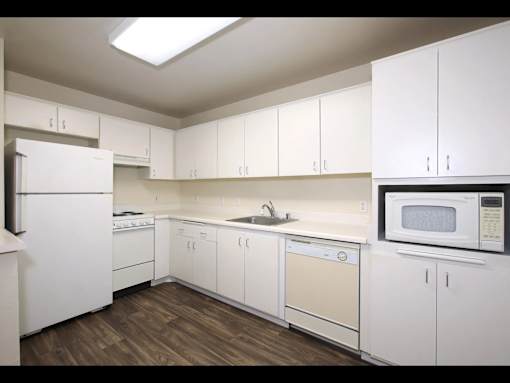 A kitchen with white cabinets and appliances.