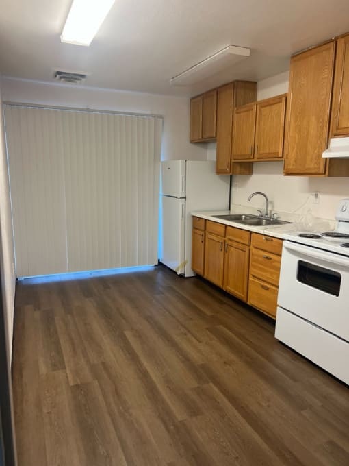 a kitchen with wood flooring and a white stove and refrigerator