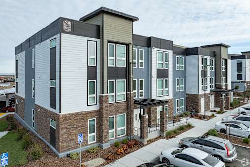 Apartment complex with a parking lot in front.