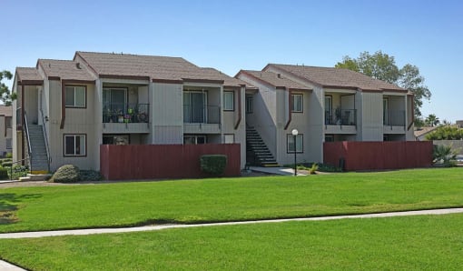 a row of apartments with balconies and green grass
