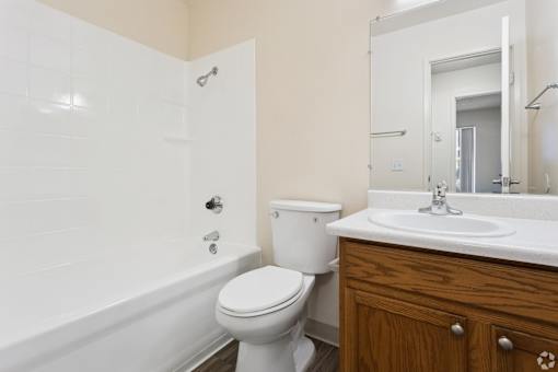 A white toilet sits next to a white bathtub in a bathroom.