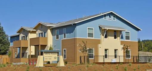 A blue and beige house with a sign in front that says "Purple Fella".