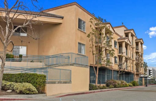 an apartment building with a staircase and trees in front of it