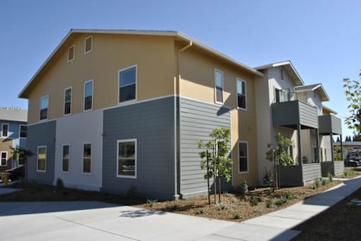 A row of houses with a sidewalk in front.
