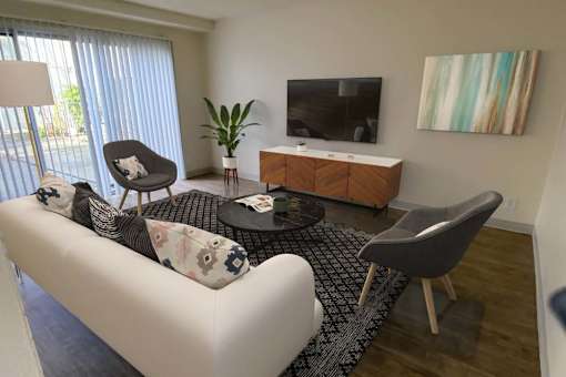 A living room with a white couch, a black and white rug, a wooden cabinet, a TV, and a painting on the wall.