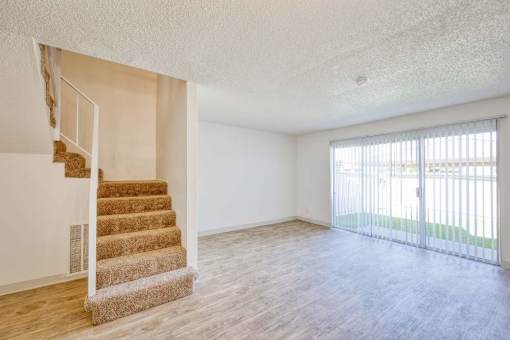 A room with a staircase and sliding glass doors.