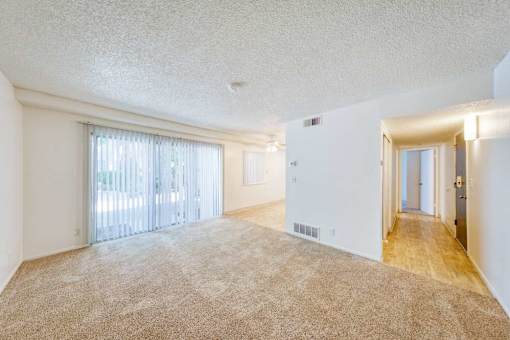 A spacious room with a carpeted floor and a sliding glass door.