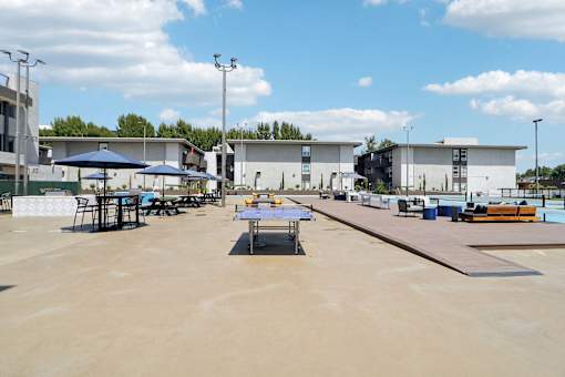 A large open area with tables and chairs and a building in the background.