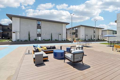 A wooden deck with a bench and a table in front of a building.