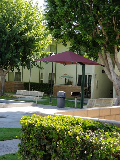 a patio with benches and an umbrella in front of a building