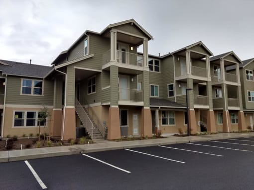 a row of apartment buildings with a parking lot in front of them