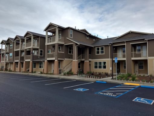 a row of apartment buildings with a parking lot in front of them