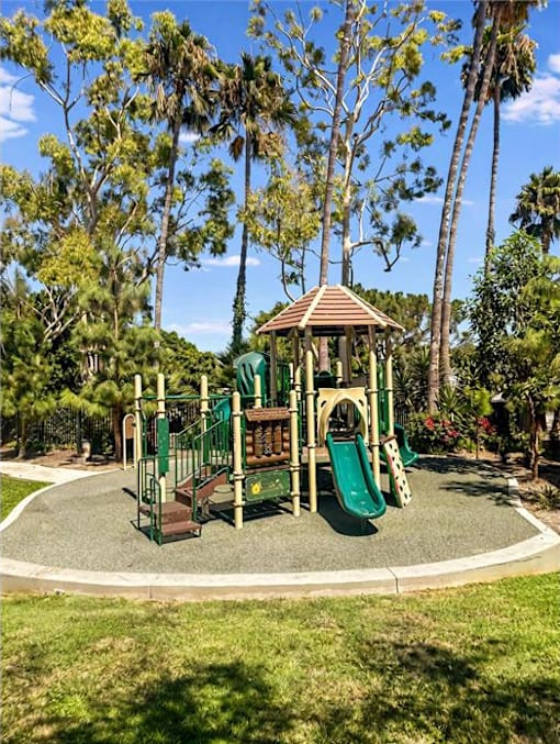 A playground with a green slide and a brown roofed structure.