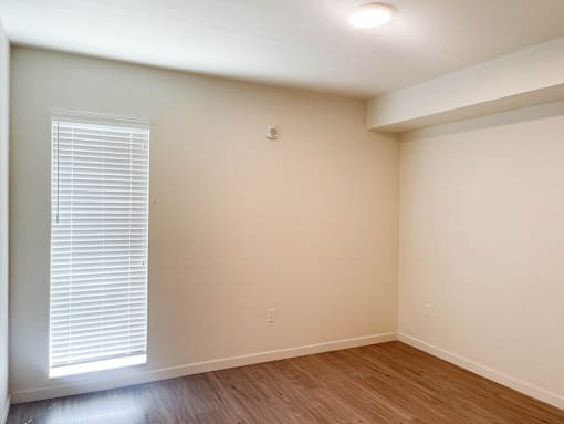 A room with a window and wooden flooring.