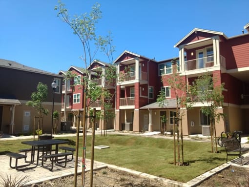 a courtyard with a picnic table in front of an apartment complex
