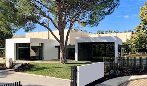A modern house with a white exterior and a black fence.