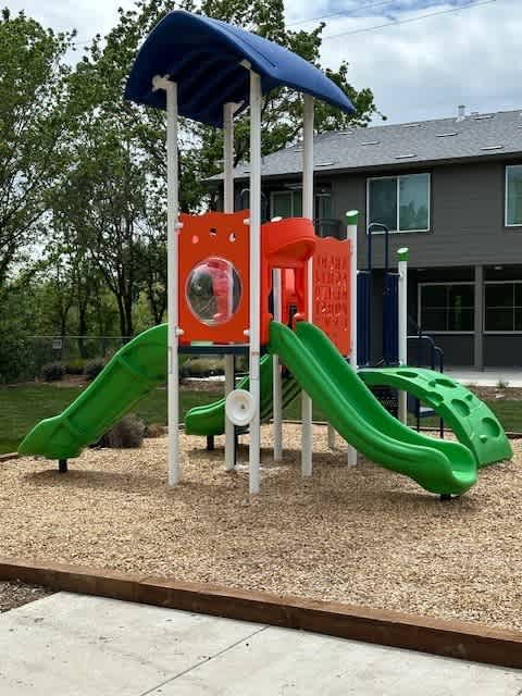 A playground with a green slide and a red and white structure.