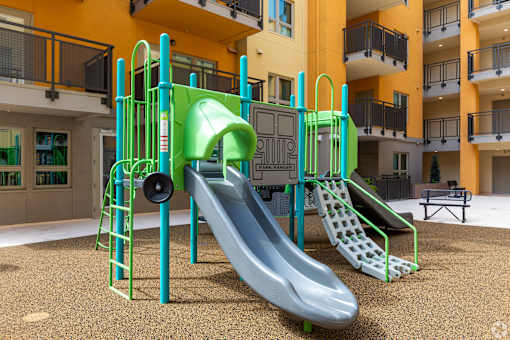 A playground with a green slide and a grey slide.