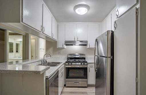 a kitchen with white cabinets and stainless steel appliances at The Arbors Santa Ana, California, 92705