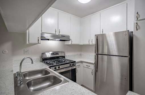 a kitchen with stainless steel appliances and white cabinets at The Arbors Santa Ana, California, 92705