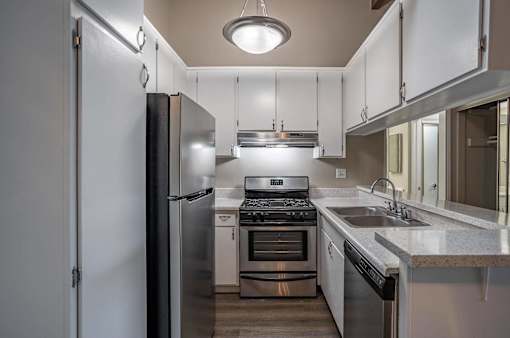 a kitchen with stainless steel appliances and white cabinets at The Arbors Santa Ana, California, 92705