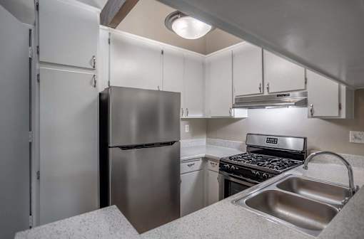 a kitchen with stainless steel appliances and white cabinets at The Arbors Santa Ana, California, 92705