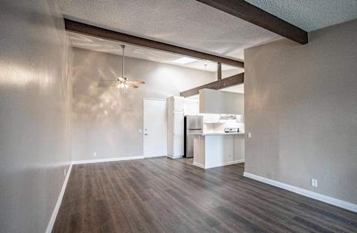 an empty living room with a ceiling fan and a kitchen at The Arbors Santa Ana, California, 92705