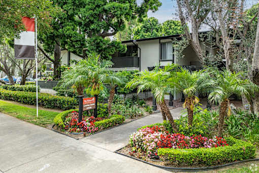 A garden with a sign in front of a building at The Arbors Santa Ana, California, 92705
