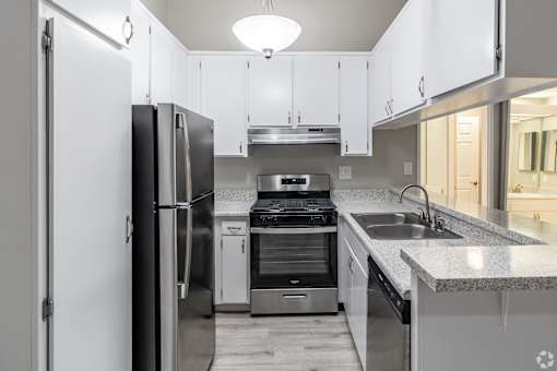 A modern kitchen with stainless steel appliances and white cabinets at The Arbors Santa Ana, California, 92705