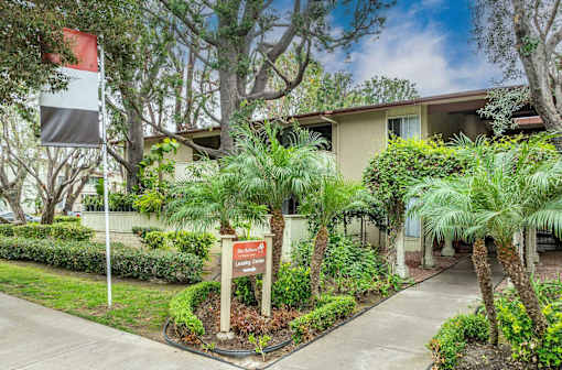 a house with a sign and palm trees in front of it at The Arbors Santa Ana, California, 92705