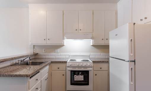 a kitchen with white cabinets and white appliances and granite counter tops