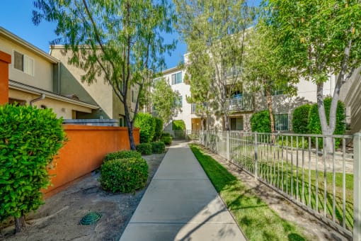 a walkway between two buildings with trees and a fence