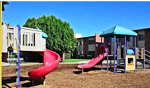 A playground with a red slide and a blue canopy.