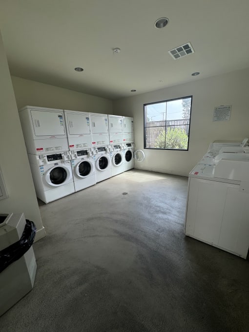 a laundry room with a row of washers and dryers and a window