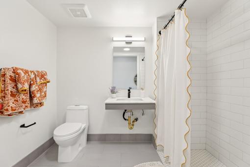 A white bathroom with a toilet, sink, and shower.