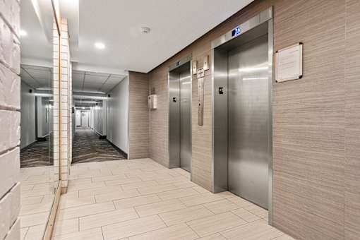 A long hallway with a series of elevators on the right side.