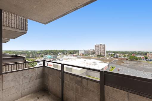 A view from a balcony overlooking a parking lot and buildings.