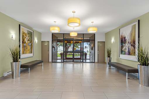 A hallway with a bench and a plant in a vase.