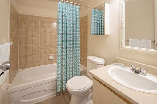A bathroom with a white toilet, a bathtub, a sink, and a shower curtain.