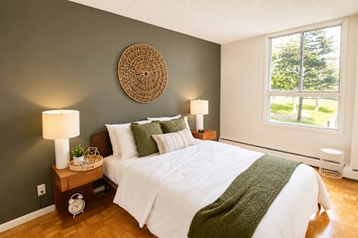A bedroom with a white bed and a green blanket.
