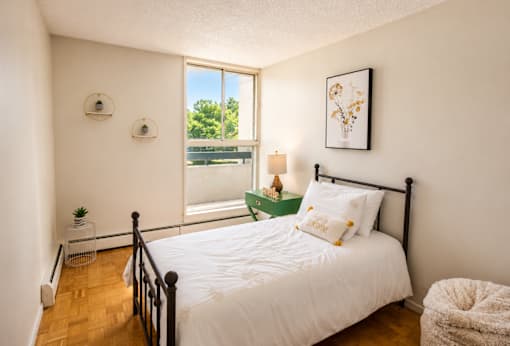 A bedroom with a large bed and a window overlooking a green area.