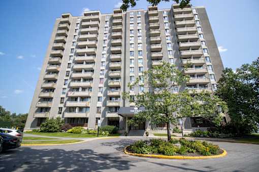 A large grey apartment building with a parking lot in front.